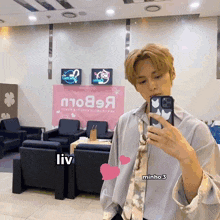 a man taking a picture of himself in front of a pink sign that says liv