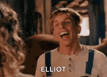 a man in overalls is laughing with a woman in a room .