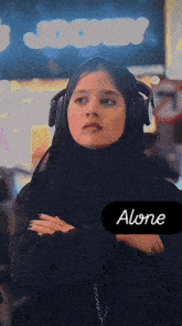 a woman wearing a hijab and headphones is alone in front of a jockey sign