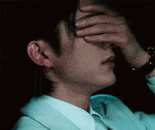 a man in a white shirt and tie is covering his face with his hand