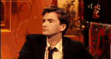a man in a suit and tie is sitting in a chair and looking to the side .