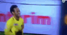 a blurry picture of a man in a yellow shirt standing in front of a sign that says ' maritima '