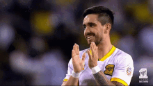 a soccer player wearing a yellow and white jersey with arabic writing on the sleeve