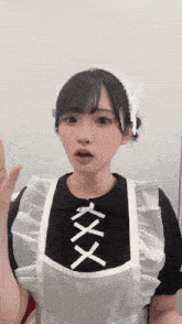 a girl wearing a maid costume with a white apron and a black shirt