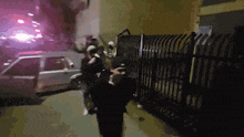 a group of people are walking down a street with a car in the background