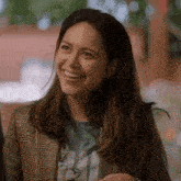a woman in a plaid jacket is smiling and looking at the camera .