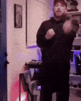 a man with a beard is dancing in a room with purple lights .