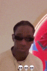 a man wearing sunglasses and a necklace with three skulls around his neck .