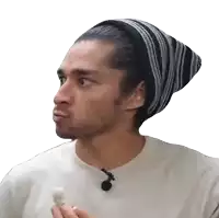 a man wearing a beanie and a white shirt is holding a marshmallow and making a funny face .