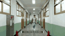 a man in a plaid shirt is dancing in a hallway with a fire extinguisher on the side