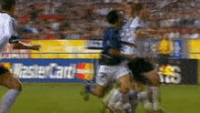 a group of soccer players are running on a field in front of a mastercard sign .