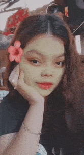 a girl with a green face mask and a flower in her hair .