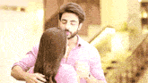 a man in a pink shirt is hugging a woman in a pink shirt