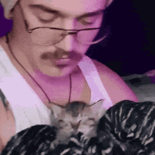 a man with glasses and a mustache is holding a kitten .