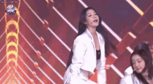 a woman in a white jacket is dancing on a stage in front of a crowd .