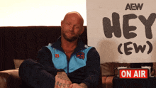 a man sits in front of a sign that says hey