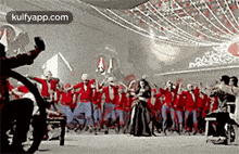 a group of people are dancing in a room with a sign that says kulfyapp.com on it .