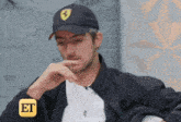 a man wearing a hat with a ferrari logo on it is sitting in a chair .