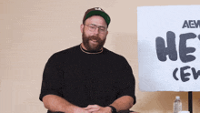 a man with a beard is sitting in front of a sign that says he 's crew