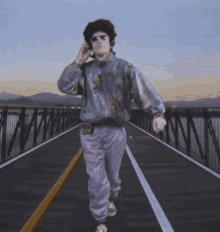 a man walking across a bridge talking on a phone