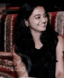 a woman is smiling while sitting on a couch with the word media visible