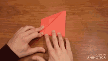 a person holding a piece of red paper with the words made in animotica on the bottom right