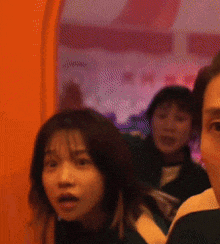 a group of people are standing in front of an orange wall looking at the camera .