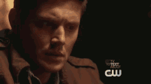 a close up of a man 's face with a tv to talk about cw logo in the background