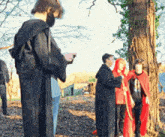 a man in a black robe stands next to a group of people