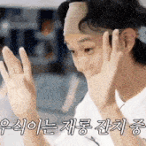a man wearing a headband is covering his face with his hands and making a funny face .