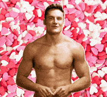a shirtless man stands in front of a pile of pink white and red hearts