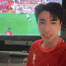 a man wearing a red shirt with the number 10 on it smiles in front of a soccer game
