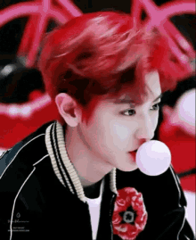 a young man with red hair is blowing a bubble with a bubble gum .