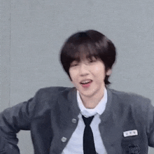 a young man wearing a school uniform and tie is dancing .