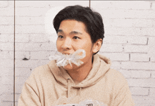 a man wearing a tan hoodie has chinese writing on his face