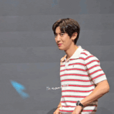 a man in a red and white striped shirt stands in front of a sign that says ' ph wanna do '
