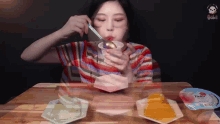a woman is sitting at a table eating ice cream with a spoon ..