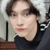 a close up of a man wearing a fur hat and a black sweater .