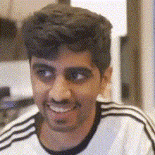 a man wearing a white shirt with black stripes on the sleeves is smiling and looking at the camera .