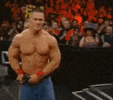 a man without a shirt is standing in front of a crowd of people .