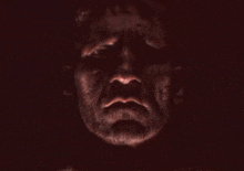 a close up of a man 's face with a beard in a dark room with his eyes closed .