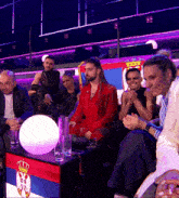 a group of people are sitting around a table with a flag on it that says serbia