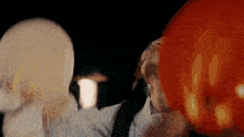 a woman is blowing up a red balloon with her mouth .