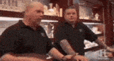 two men in black shirts are standing next to each other in a jewelry store .