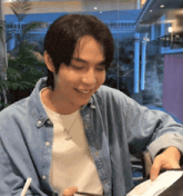 a man in a denim shirt is smiling while holding a plate