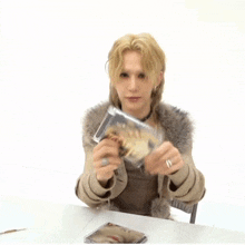 a person sitting at a table holding a cd that says ' a ' on it