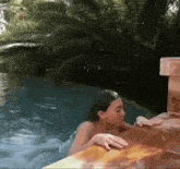 a woman is swimming in a swimming pool with a palm tree in the background