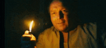 a man is holding a lighter in his hand in the dark and looking at it .