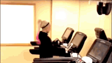 a woman is sitting on a treadmill in a gym with a mirror behind her