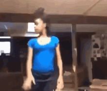 a girl in a blue shirt is standing in a room .